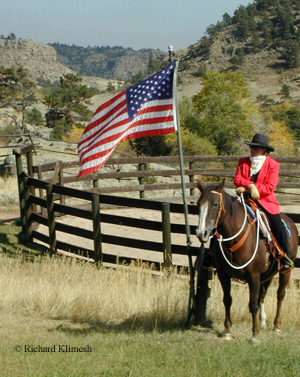Cherry Hill on her horse Zinger beside a waving flag